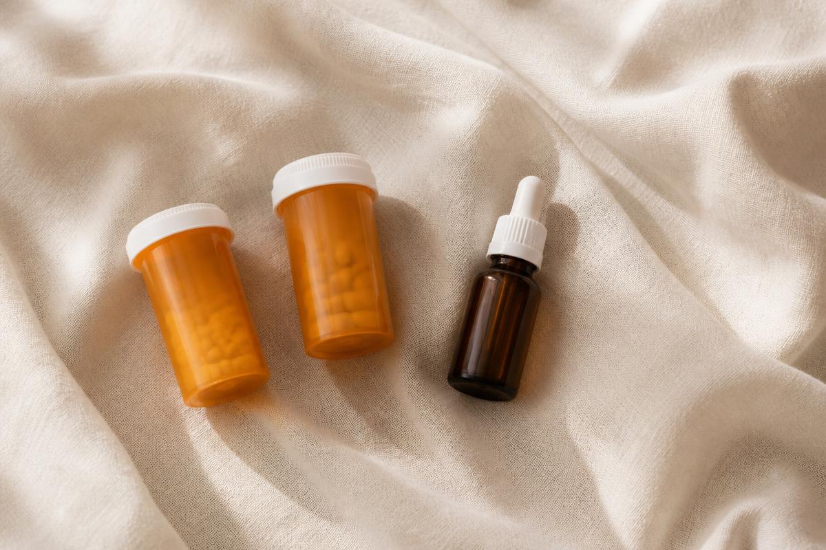 Two prescription pill bottles and a small topical solution bottle on a cream linen surface